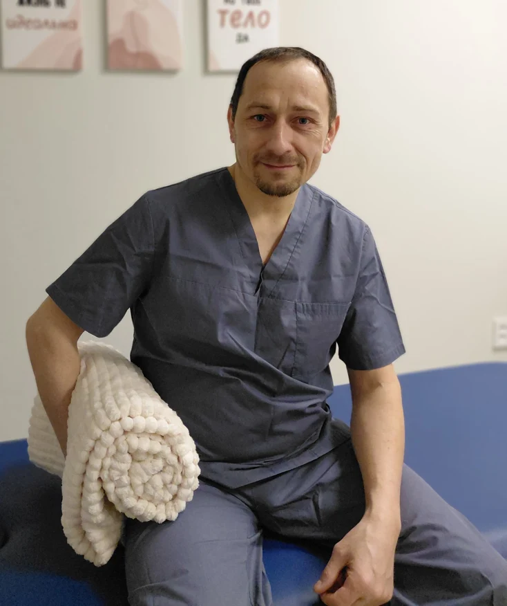Владимир Курто сидит рядом с белым пледом на синей кушетке